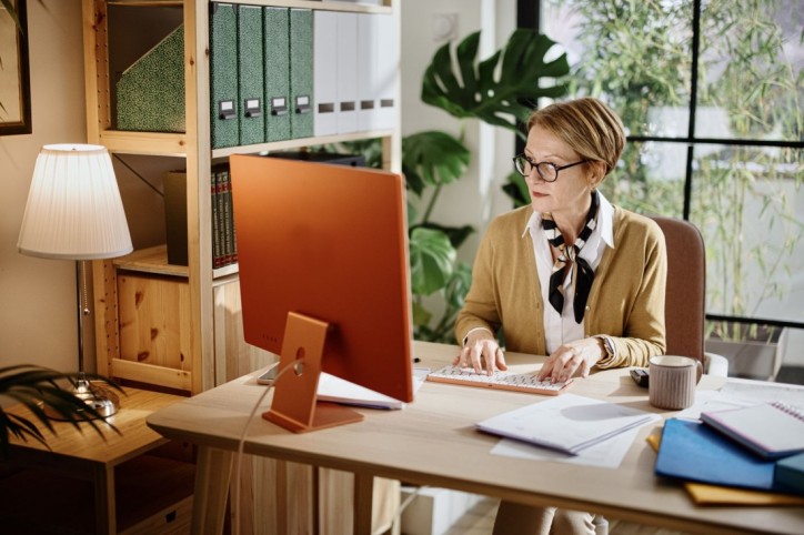Eine ältere Frau arbeitet komnzentriert im Büro am Computer.