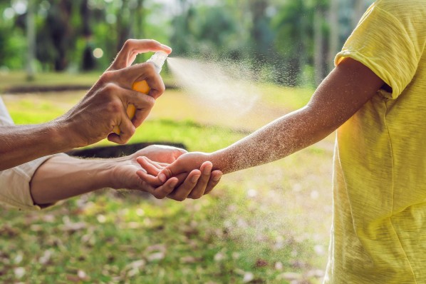 Mutter sprüht Sohn mit Sonnenspray ein