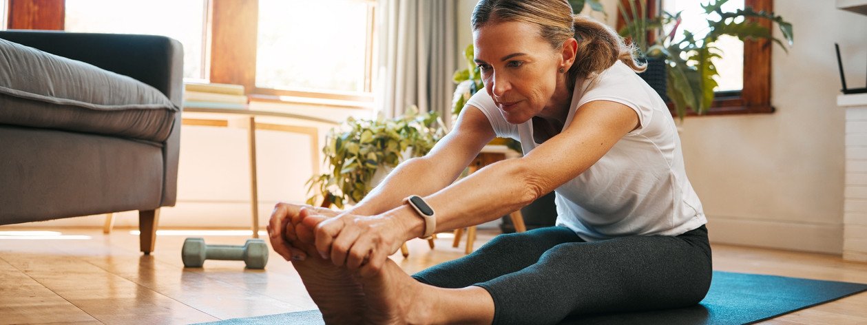 Eine Frau führt zuhause auf der Matte Mobility Training durch.