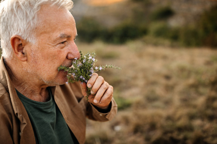 Ein Senior riecht an einem Strauß Blumen