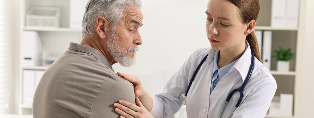 Eine Ärztin behandelt einen älteren Mann in der Schmerzsprechstunde