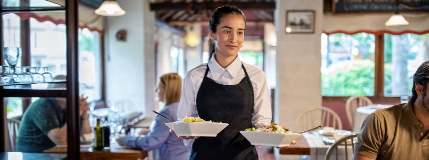Eine Kellnerin serviert zwei Salatschüsseln in einem Restaurant.