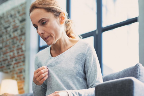 Eine Frau Mitte 40 zupft nervös am Kragen ihres Pullovers.