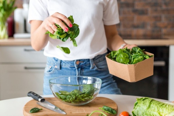 Nahaufnahme einer FRau, die Salat zubereitet.