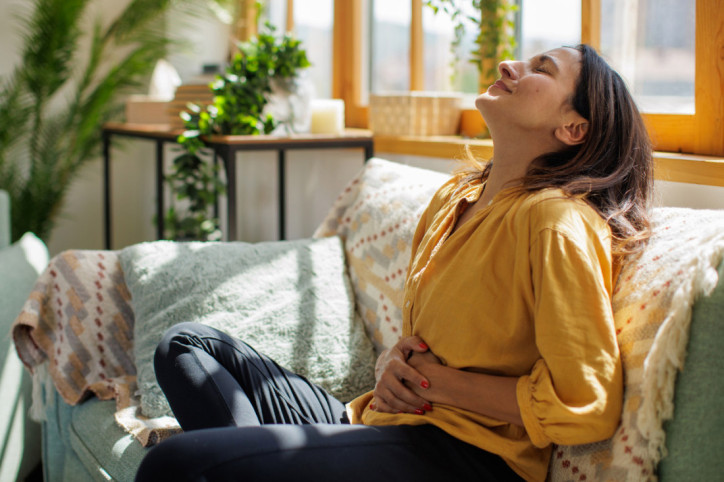 Eine Frau mit aus dem Takt geratenen Mikrobiom hält sich den Bauch