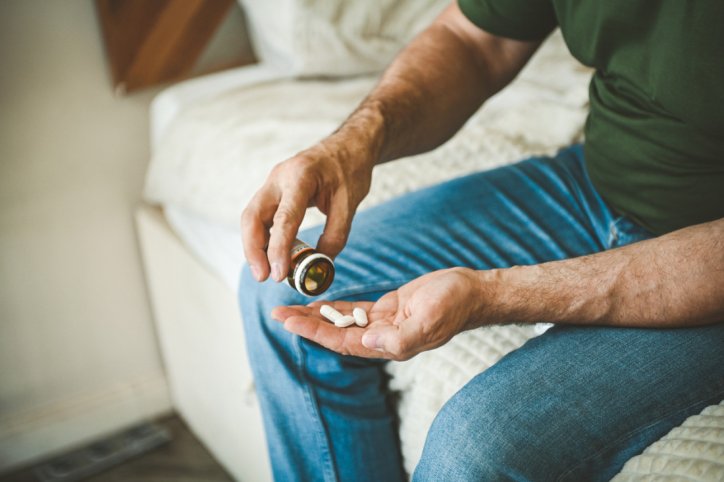 Ein Mann schüttet sich seine Tabletten in die Hand.