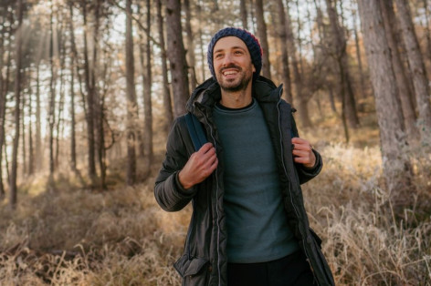 ein junger Mann wandert allein durch den wald. es ist kalt.