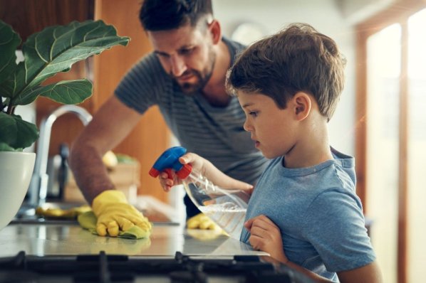 Vater und Sohn putzen in der Küche.