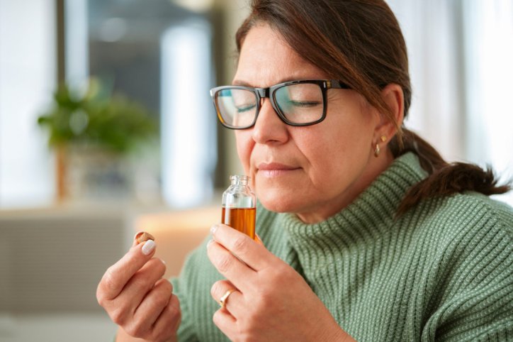 Eine Frau riecht an einer kleinen Flasche.