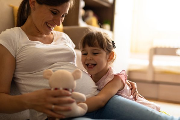 Schwangere Frau und Tochter freuen sich auf das Baby.