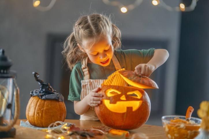 Ein Kind schnitzt einen Kürbis für Halloween.