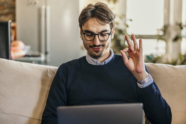 Mann am Laptop macht Kreis aus Daumen und Zeigefinger