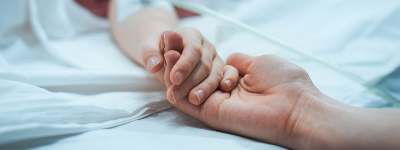 Die Hand von einem Kind im MRT wird von einem Elternteil gehalten