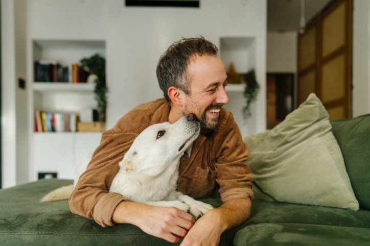 Ein anfang 40-jähriger Mann  mit seinem weißen Hund auf dem Sofa