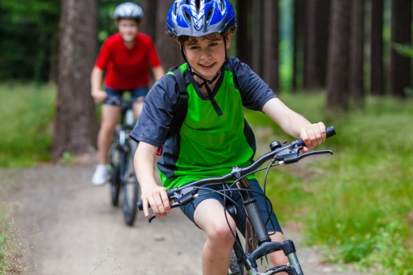 Ein Junge fährt mit seinem Mountainbike durch einen Wald.