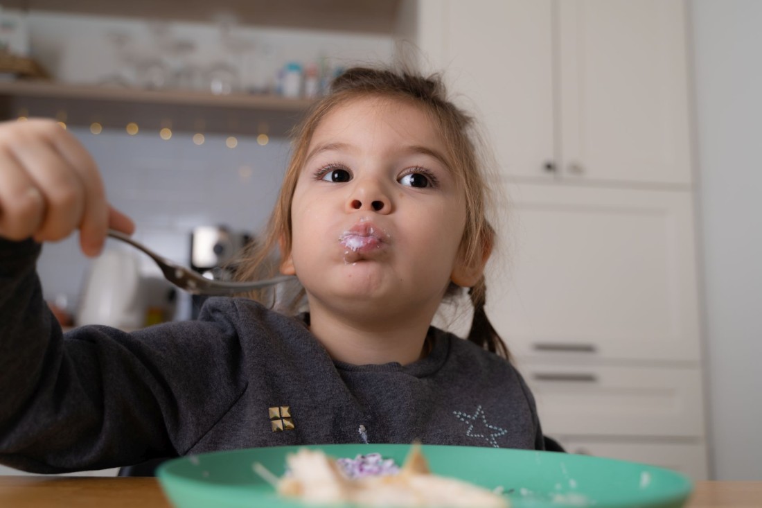 Ein etwa 3-jähriges Mädchen isst Müsli.