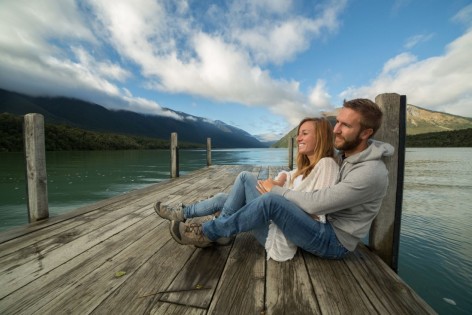 Ein Paar sitzt zusammen auf einem Steg am See.