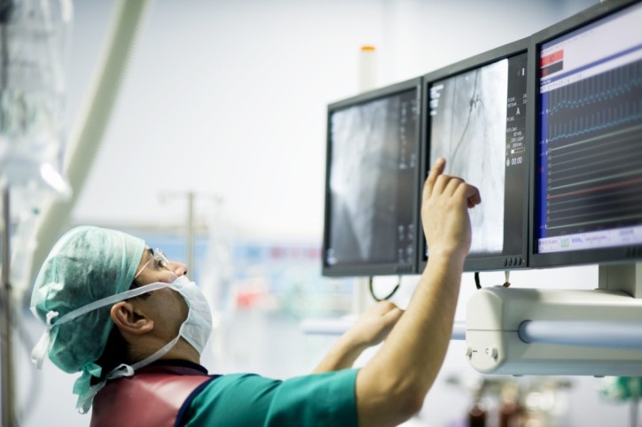 Arzt im OP kontrolliert die Werte des Patienten an einem Computer-Bildschirm.