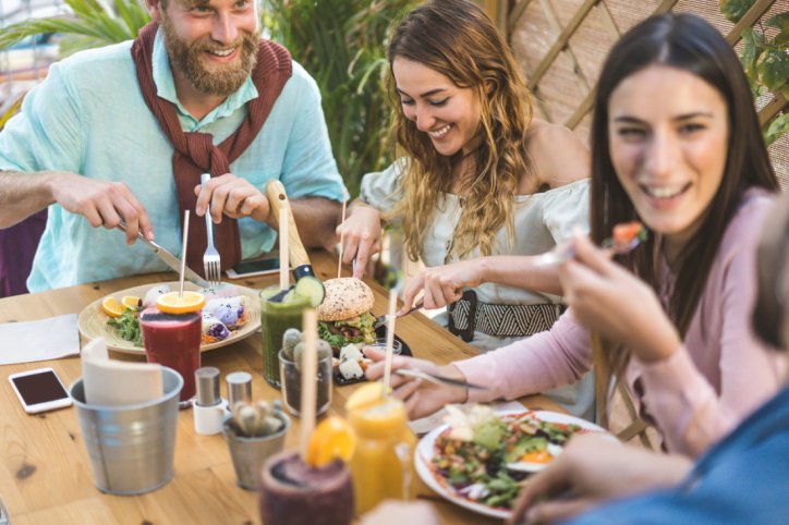 Eine Gruppe fröhlicher Menschen isst geneinsam in einem vegetarischen Restaurant in Sachsen-Anhalt