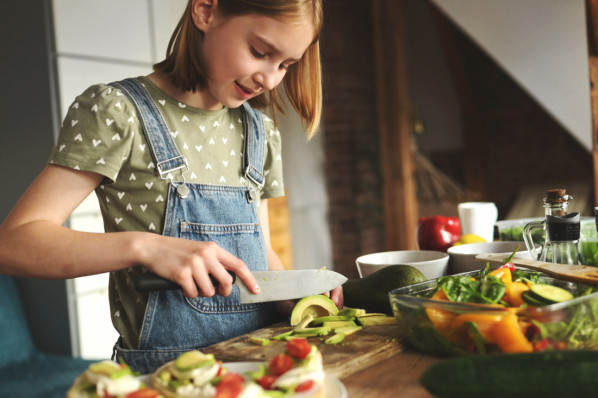 Mädchen schneidet Avocado in der Küche