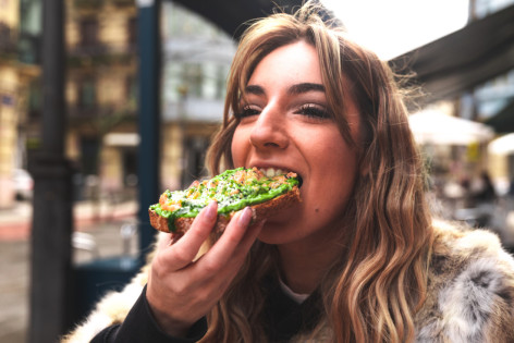 Frau mitte 20 beißt in ein Avocadobrot