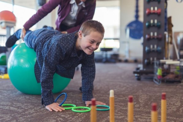 Ein Junge mit Down-Syndrom macht Übungen auf einem Gymnastikball.