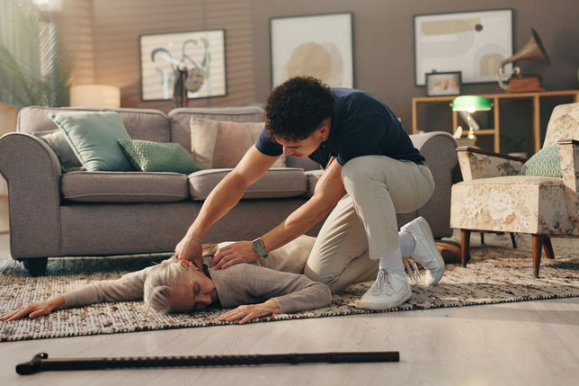 Ein junger Mann hilft einer ohnmächtigen Seniorin