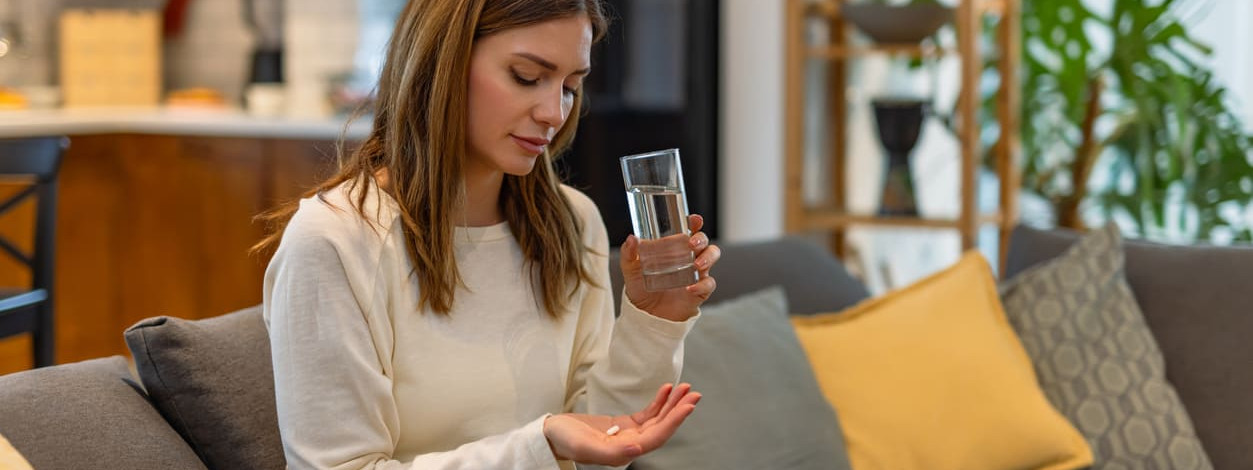 Eine Frau nimmt ein Antibiotikum mit Wasser ein