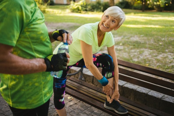 Athlete senior woman tying sport shoe shoelace in the park