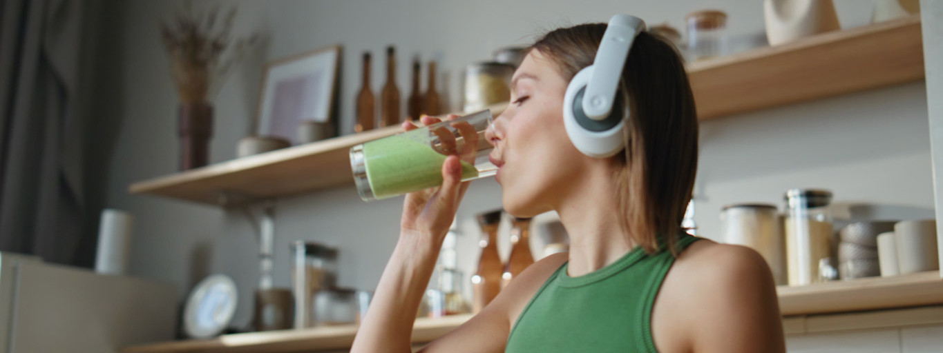 Eine Junge Frau trinkt einen Smoothie, um einem Vitaminmangel vorzubeugen