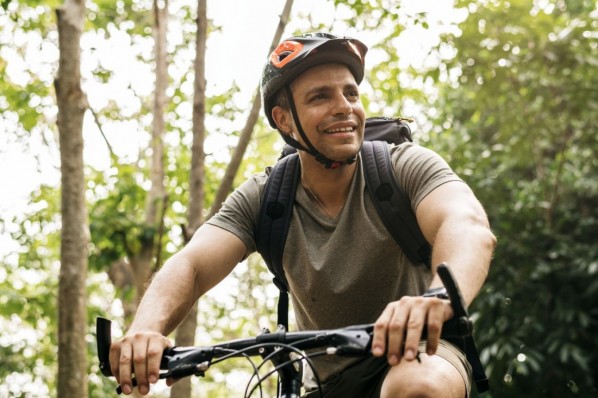 Ein etwa 35-jähriger Mann ist mit dem Mountainbike in der Natur unterwegs.