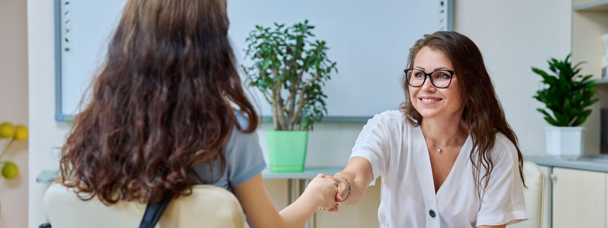 Eine Beraterin begrüßt eine junge Frau bei der Ausbildungsmesse
