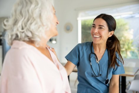 Eine Ärztin unterhält sich lachend mit einer Patientin.