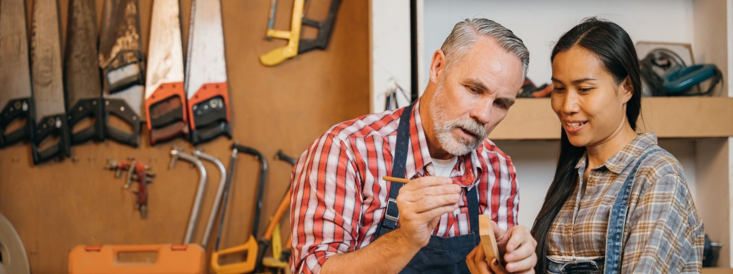 Ein Handwerker erklärt einer Arbeitskollegin einen Arbeitsprozess.