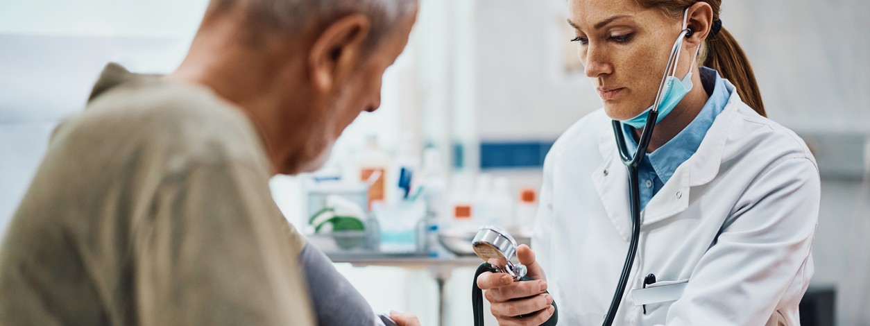 Eine Ärztin misst bei einem Patientin den Blutdruck.