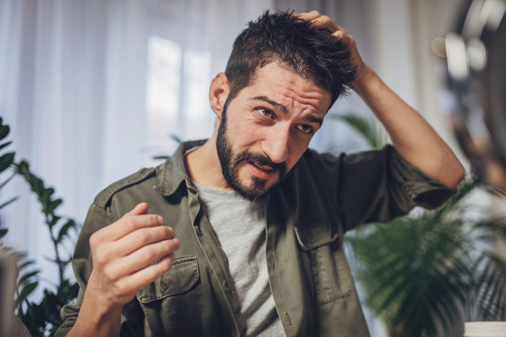 Ein Mann fasst sich an seine juckende Kopfhaut.