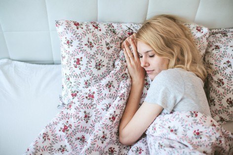 Eine blonde Frau liegt im Bett und schläft.