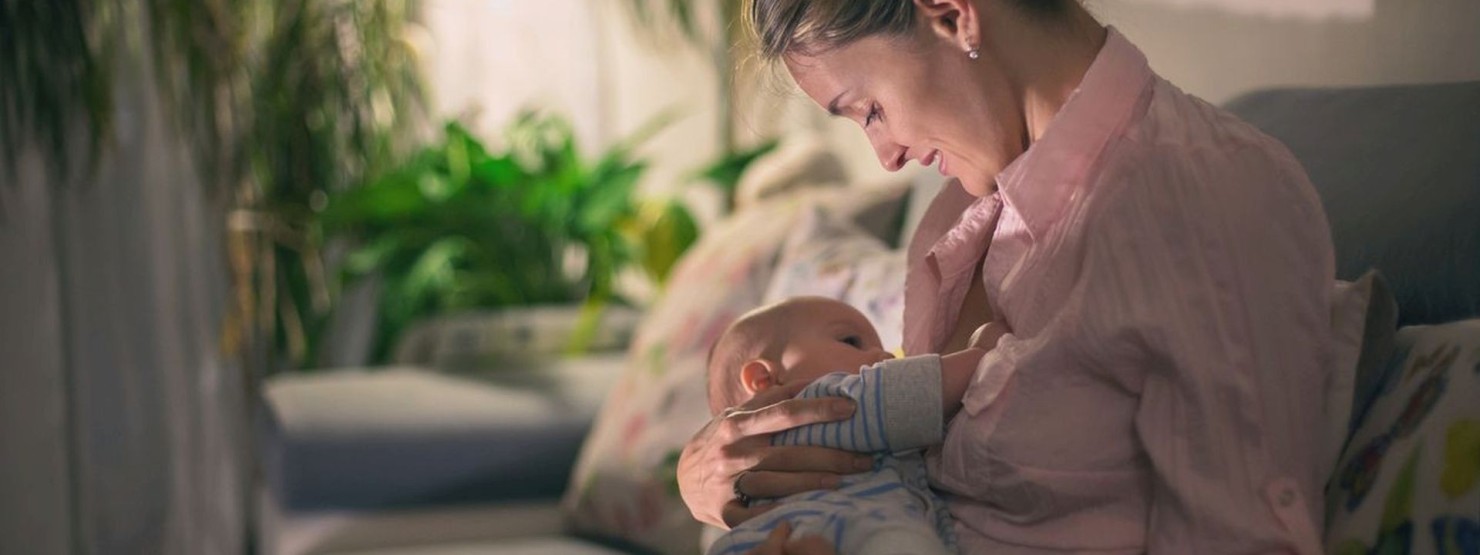 Frau mit ihrem Baby gemütlich im Bett.