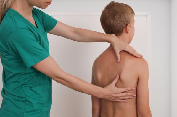 Eine Ärztin testet einen Jungen auf Skoliose