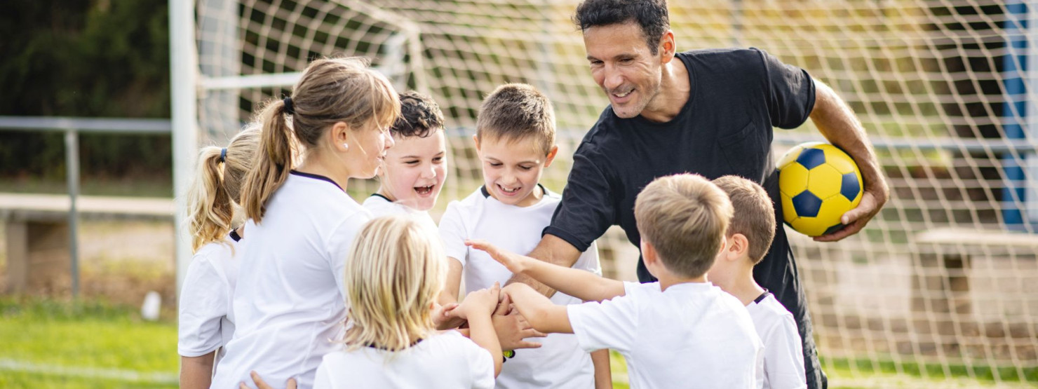 Eine Kinderfußballmannschaft freut sich gemeinsam mit ihrem Trainer.