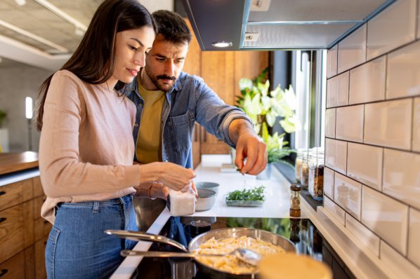 Paar kocht zusammen in der Küche und würzt die Speisen
