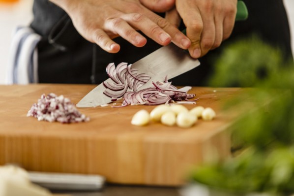 Frauenhände schneiden frische Zwiebeln und Knoblauch