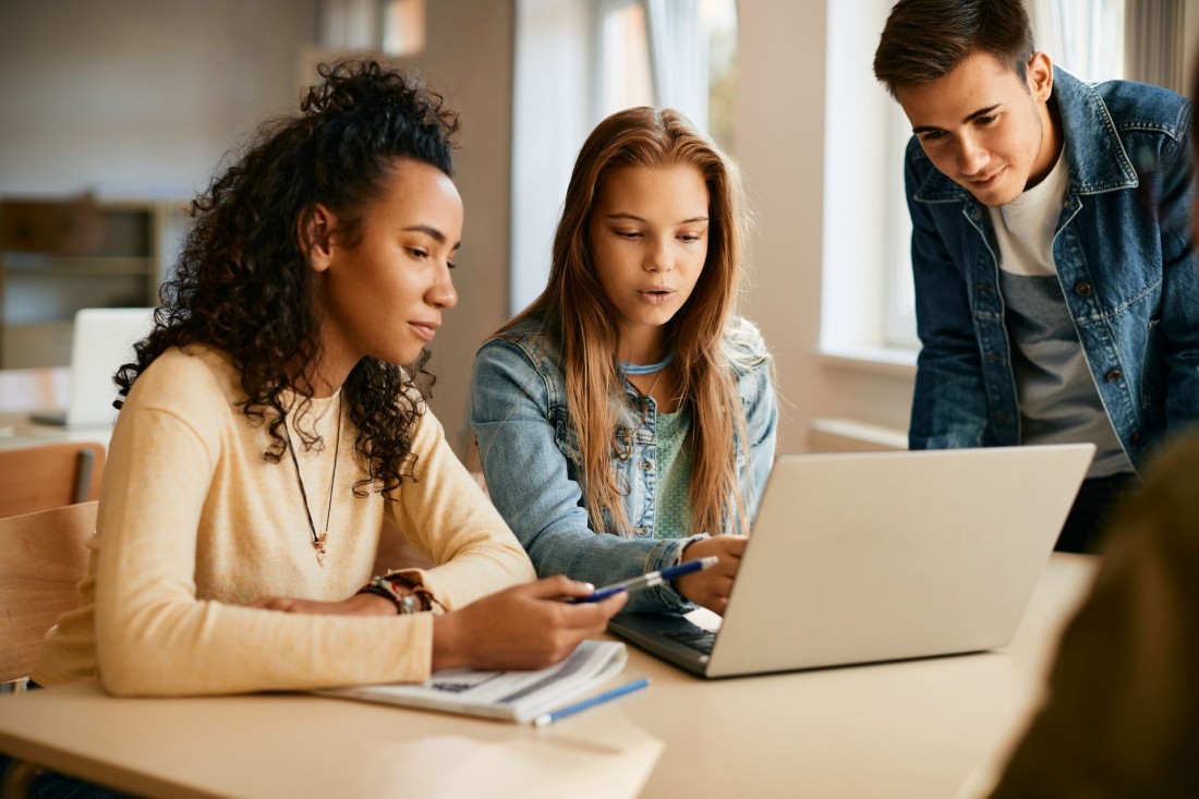 3 Jugendliche sitzen vor einem Laptop und prüfen kritisch eine Nachricht.