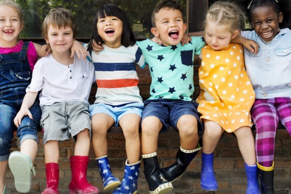 6 Kindergartenkinder sitzen auf einer Bank.