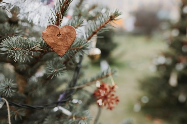 Handmade gingerbread heart shaped cookie decoration on a Christmas tree. Outdoor background without snow. Diy creative ideas for children. Environmental concept. Selective focus, copy space
