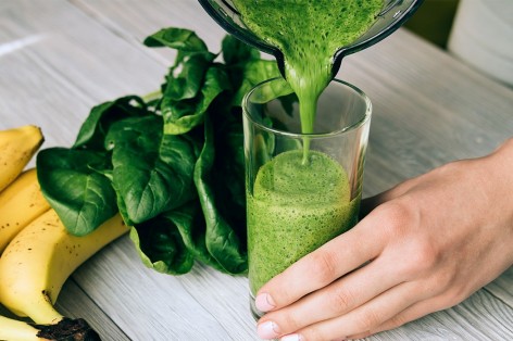 Grüner Smoothie wird in ein Glas gegoßen