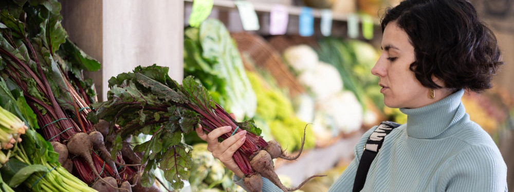 Eine Frau kauft Knollen- und Wurzelgemüse im Supermarkt