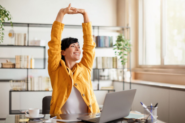 Stress Relief. Relaxed middle aged businesswoman taking break at workplace, stretching her body, sitting at desk with laptop in modern home office indoors. Relax after good day at work