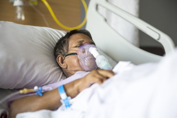Eine Patientin liegt in einem Krankenhausbett und wird beatmet.