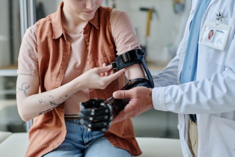 Eine Frau legt mit Hilfe eines Arztes ihre Armprothese an.
